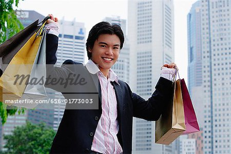 Homme portant des sacs à provisions, souriant à la caméra