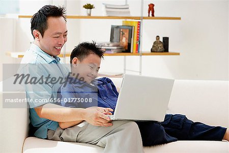 Vater und Sohn im Wohnzimmer, Blick auf laptop