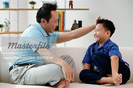 Vater und Sohn sitzen auf dem Sofa, von Angesicht zu Angesicht