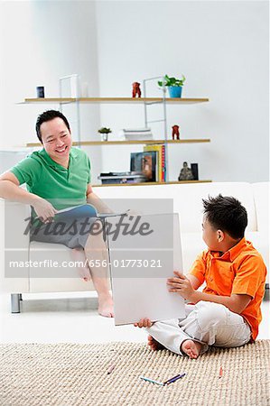 Vater sitzen auf dem Sofa, Sohn Stock Pad Zeichnung hält