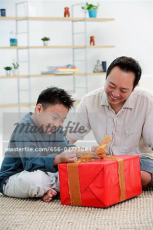 Garçon, ouverture de boîte de cadeau, père à côté de lui