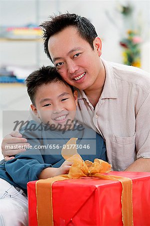 Vater und Sohn neben Geschenk-Box, Blick in die Kamera