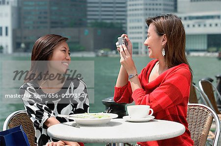 Two women at outdoor cafe, using a camera
