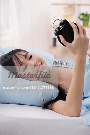 Jeune femme allongée sur le lit, radio-réveil, en regardant souriant