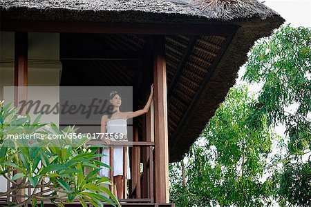 Young woman standing in balcony, looking out