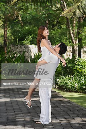 Couple in garden, man lifting woman up