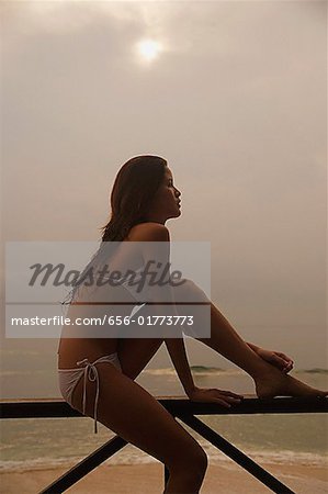 Woman sitting on beach, looking away