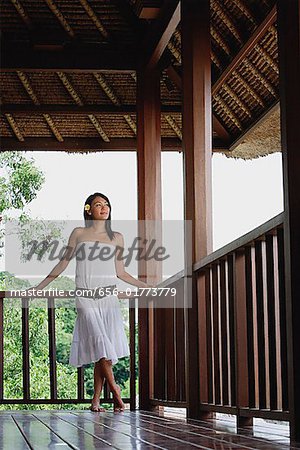 Jeune femme en robe blanche debout au balcon, à la recherche de suite