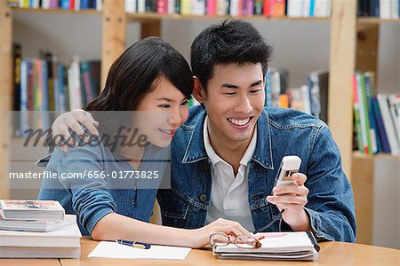 Couple dans la bibliothèque, regarder téléphone mobile