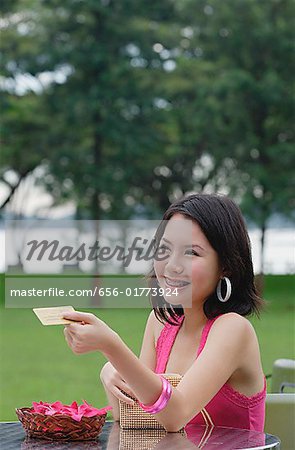 Young woman sitting at outdoor table, paying with credit card