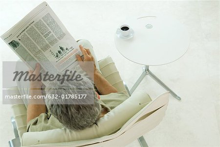 Man sitting, reading newspaper, high angle view