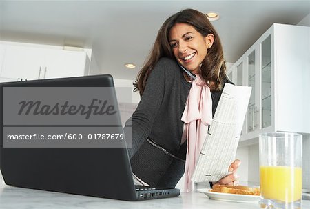 Businesswoman at Home, Using Laptop Computer and Talking on Cell Phone