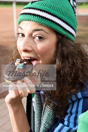 Jeune fille mangeant un beignet qui est décorée avec un Football Player Figurine