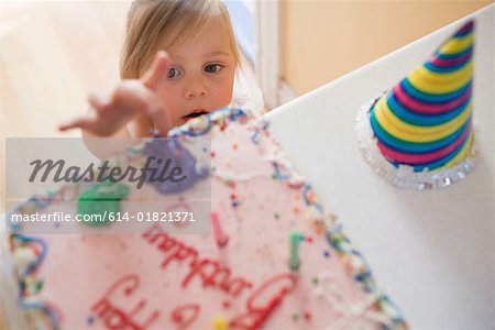 Girl touching birthday cake