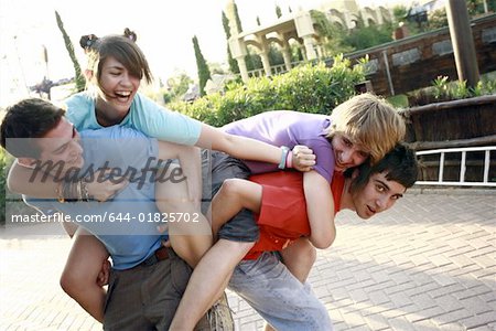 Teenagers playing on piggy back in amusement park