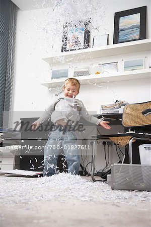 Boy Throwing Shredded Paper in Office