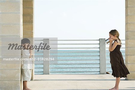 Two children playing with tin can phone, side view