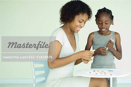 Mère et fille jouer pick up sticks ensemble à table, les deux souriant
