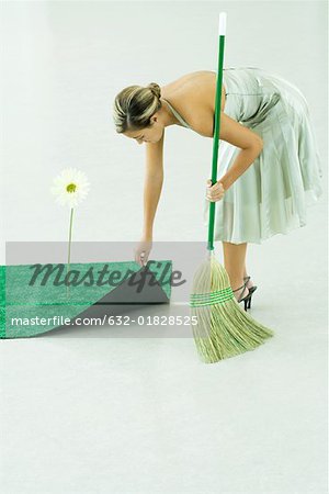 Woman sweeping under rug of artificial turf