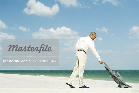 Man vacuuming beach, full length