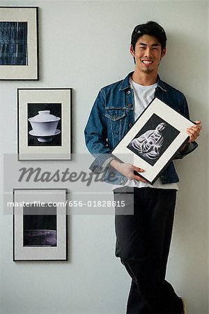 Young man holding framed photographs