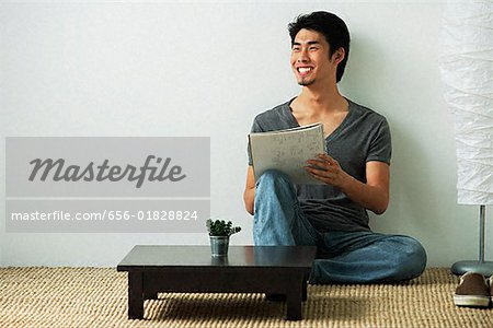 Junger Mann sitzt auf dem Boden während des Schreibens