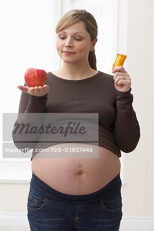 Pregnant Woman Holding Pills and an Apple
