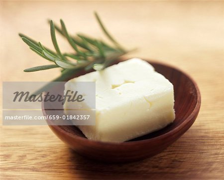 Beurre frais dans un bol en bois au romarin