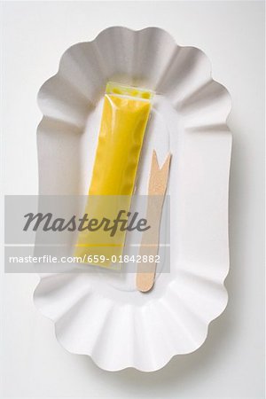 Fourche en bois et sachet de moutarde sur une assiette en carton