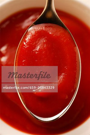 Ketchup in small bowl and on spoon (close-up)