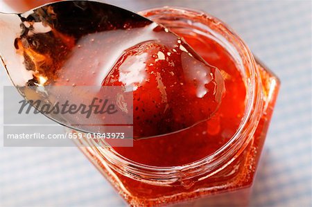 Strawberry jam in jar and on spoon