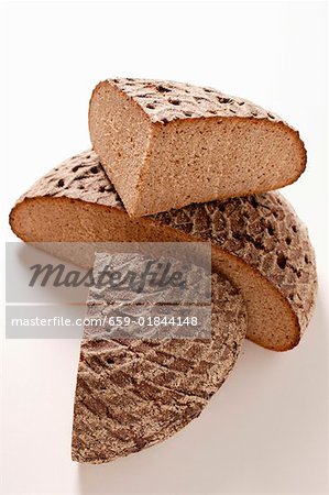 A loaf of farmhouse bread, halved and two quarters