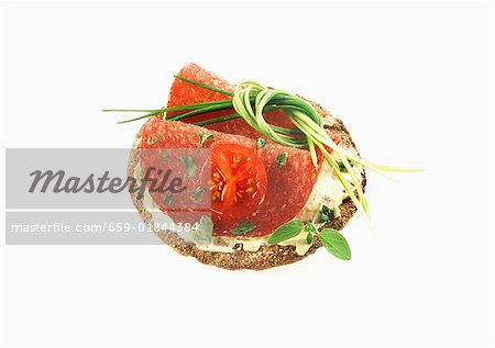 Cracker avec salami, tomates et fines herbes