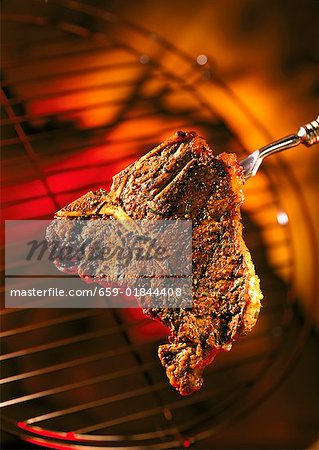 Barbecued T-bone steak on fork Barbecued T-bone steak on fork