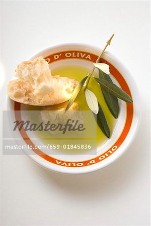 Olive oil in bowl with white bread and olive branch