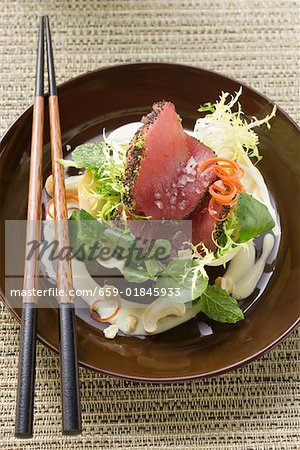 Raw tuna fillets with poppy seeds on salad in bowl