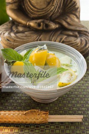 Coconut soup with fish & Thai aubergines in front of Buddha