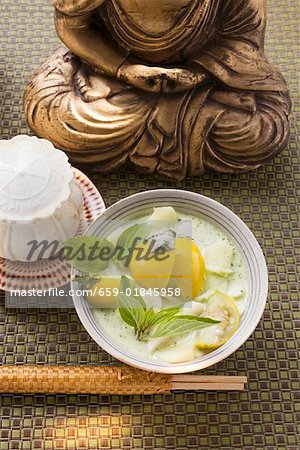Soupe de noix de coco avec poisson et aubergines Thaïs devant Bouddha
