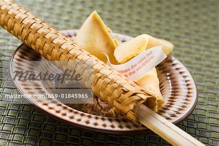 Fortune cookies and chopsticks in woven wrapper on plate