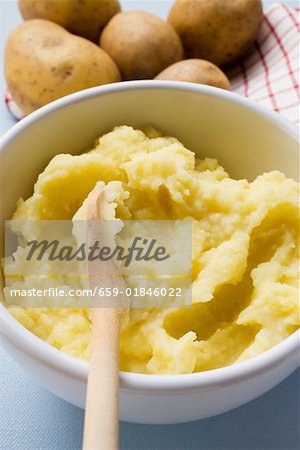 Mashed potato in bowl with wooden spoon