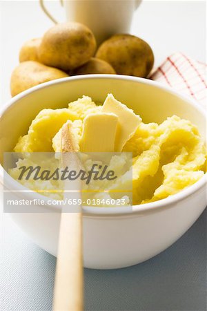 Purée de pommes de terre avec du beurre dans un bol avec une cuillère de bois