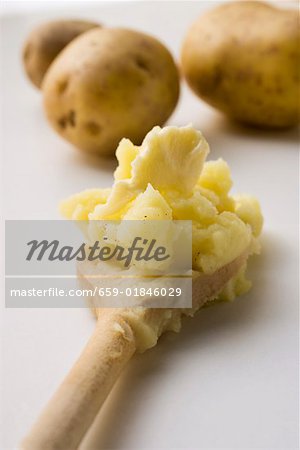 Mashed potato with butter on wooden spoon