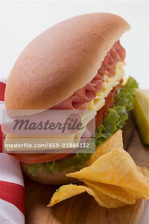Sub-Sandwich mit Chips und Gurke auf Schneidebrett