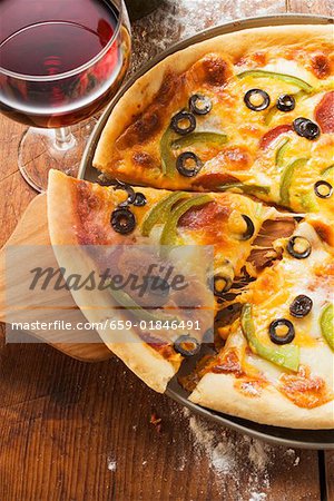 Pizza with cheese, salami, peppers & olives, glass of red wine