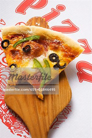 Piece of pizza with cheese, salami, peppers, olives on server