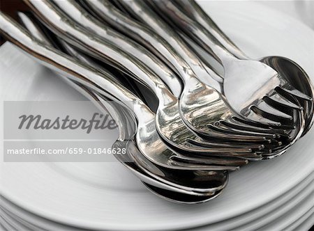 Pile of plates with spoons and forks