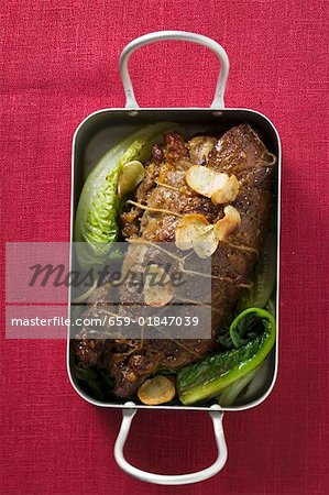 Roast lamb with garlic and vegetables in roasting dish