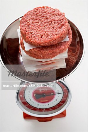 A pile of raw burgers for hamburgers on kitchen scales