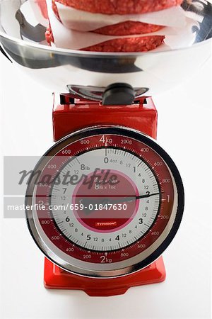 Kitchen scales with raw burgers