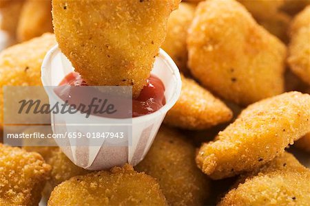 Dipping a chicken nugget in ketchup